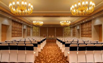 a large , empty banquet hall with rows of white chairs and chandeliers hanging from the ceiling at Radisson Blu New Delhi Dwarka