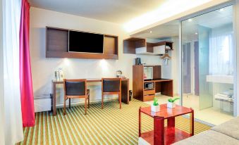 a small hotel room with a green and white striped floor , a desk , a television , and a refrigerator at Hôtel Mercure Paris Ivry Quai de Seine