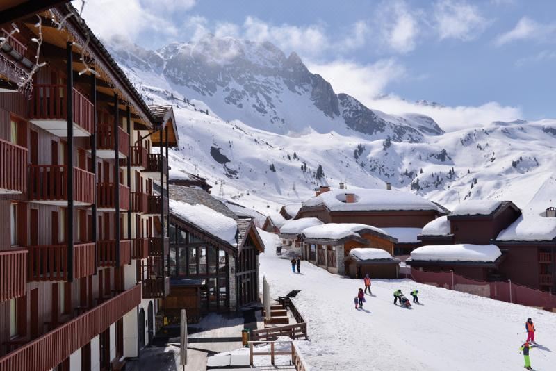 a snow - covered mountain village with a group of people skiing and snowboarding down the slopes at Hotel l'Eden des Cimes - Vacances Bleues - Belle Plagne 2100