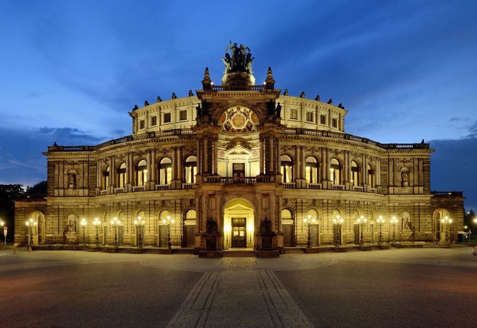 a large , ornate building with a statue in front of it and the night sky behind at Hotel Kaiserhof