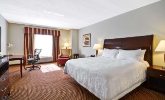 a large bed with white linens is situated in a hotel room next to a window at Hilton Garden Inn Tampa/Riverview/Brandon