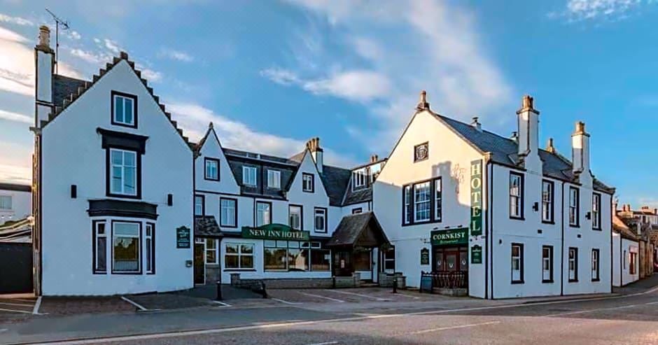 a white building with a green sign on the front , located in a town square at New Inn Hotel