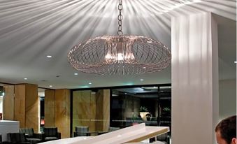 a man is playing the piano in a room with a chandelier hanging from the ceiling at The Executive Inn, Newcastle