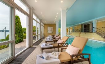 a row of lounge chairs with towels on them are lined up in a room next to a pool at Seehotel Leoni