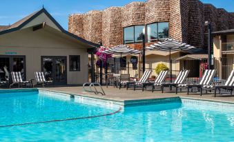 a large outdoor swimming pool surrounded by chairs and umbrellas , providing a relaxing atmosphere for guests at Red Lion Hotel Port Angeles Harbor