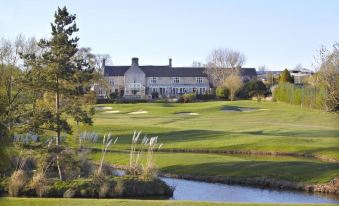 a beautiful golf course with a large building in the background , surrounded by trees and grass at Horsley Lodge