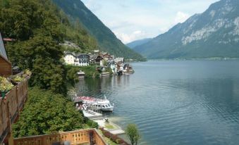 a beautiful lake surrounded by mountains , with a boat docked on the shore and a cabin in the background at Seehotel Gruner Baum