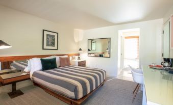 a modern bedroom with white walls , wooden furniture , and a large bed dressed in striped bedding at Little Beaver Inn