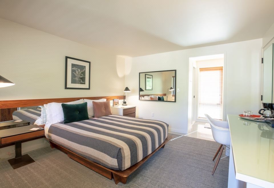 a modern bedroom with a wooden bed , white walls , and a large mirror on the wall at Little Beaver Inn