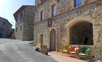 a stone building with a sign on the front , surrounded by potted plants and chairs at Bosco Della Spina