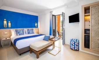 a hotel room with a blue and white theme , featuring a king - sized bed , a television , and a bathroom at Sol Oasis Marrakech - All Inclusive