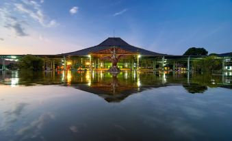 a large , modern building with a traditional building and a well - lit reflection in the water at The Sunan Hotel Solo