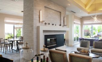 a modern living room with a fireplace , dining area , and several chairs arranged around it at Hilton Garden Inn Philadelphia/Ft. Washington