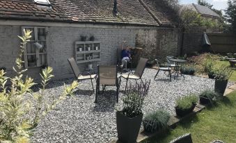 a small backyard with a paved patio , chairs , and a table set up for outdoor dining at The Ardingly Inn