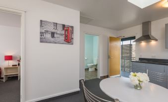 a modern kitchen with white walls , gray cabinets , and a red phone booth picture on the wall at Greens Motel