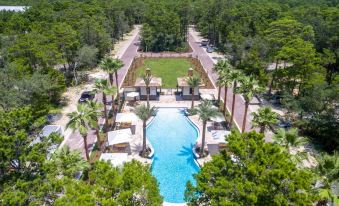 aerial view of a resort with a large pool surrounded by palm trees and grass at Magnolia Cottages by the Sea by Panhandle Getaways