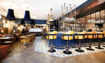 a modern bar with blue and yellow furniture , wooden tables , and chairs , as well as a bar area with multiple stools at Beadnell Towers Hotel