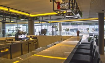 a modern kitchen with a long counter and yellow accents , featuring potted plants hanging from the ceiling at Slaviero Campina Grande