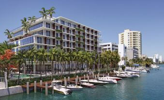 a large building with many windows is situated next to a marina filled with boats and palm trees at Grand Beach Hotel Bay Harbor