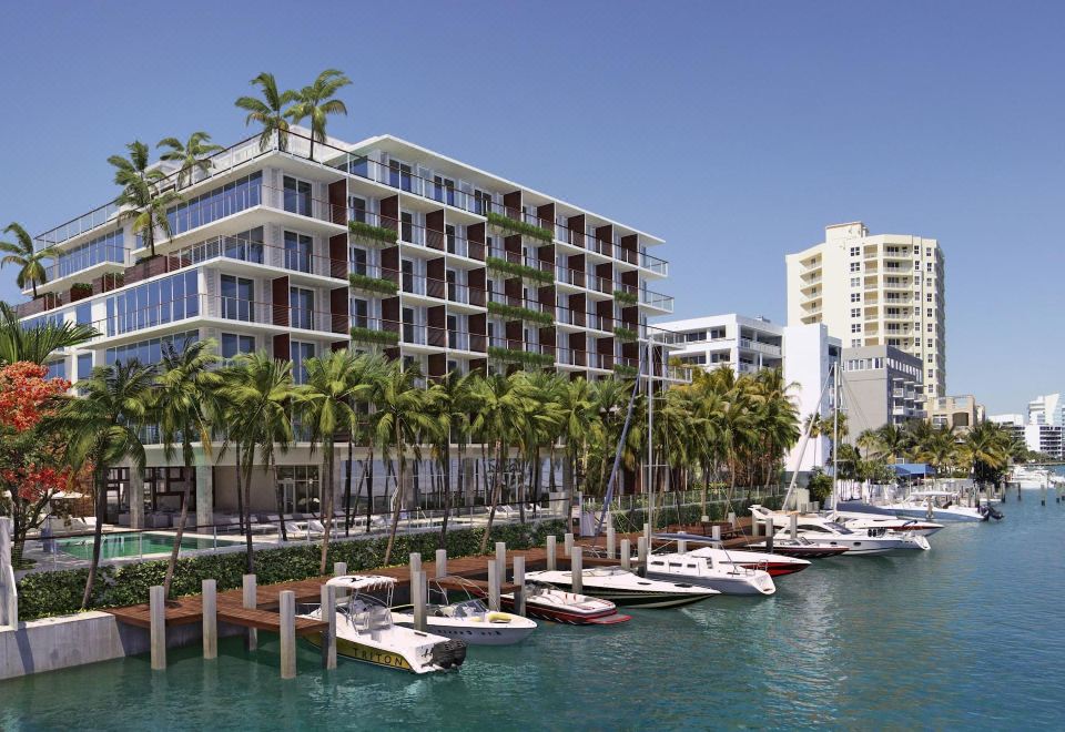 a large building with many windows is situated next to a marina filled with boats and palm trees at Grand Beach Hotel Bay Harbor