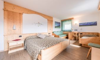 a modern hotel room with wooden furniture , including a bed , desk , and window , as well as a comfortable bed with leopard print bedding at Hotel Alpino