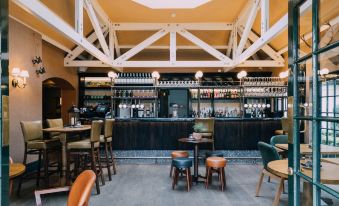 a modern bar with wooden beams , black tables , and chairs , along with a bottle of wine on the counter at The Woburn