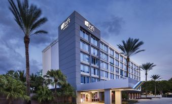 a large hotel building with palm trees in front of it , creating a tropical atmosphere at Aloft Miami Dadeland