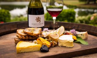 a wooden tray with a bottle of wine and a plate of cheese and fruit at City View Motel