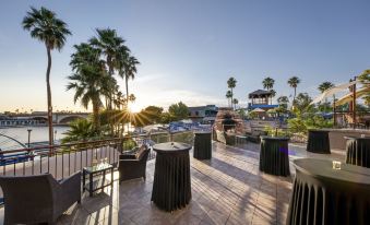 a patio with tables and chairs is set up on a balcony overlooking palm trees and buildings at London Bridge Resort