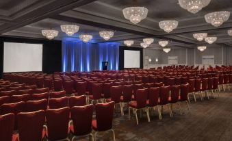 a large conference room with rows of red chairs and blue lights on the ceiling at Marriott Boston Quincy