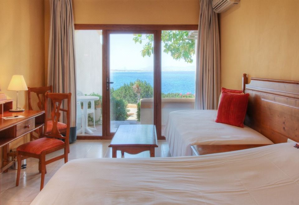 a bedroom with two beds and a view of the ocean through a sliding glass door at Hotel Club Sunway Punta Prima