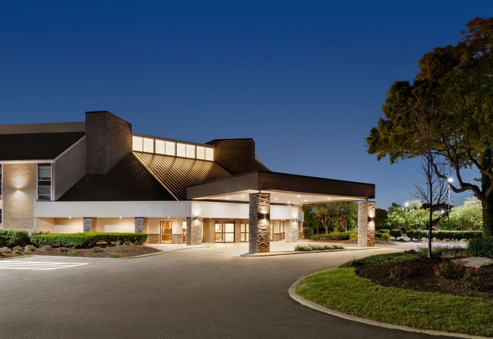 a modern hotel building with a large sign above the entrance , surrounded by trees and grass at Doubletree by Hilton Columbus Dublin