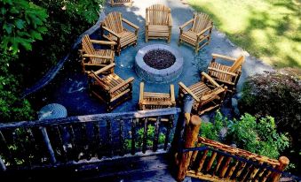 a wooden adirondack chair set with a fire pit surrounded by benches on a patio at Weasku Inn