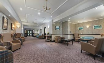 a spacious , well - lit lobby with comfortable seating areas and a staircase leading to the second floor at The Tarbet Hotel