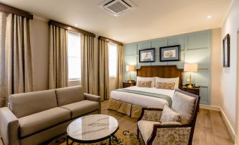 a large bed with a beige comforter is in the center of a room with a couch and chairs at Gold Reef City Theme Park Hotel