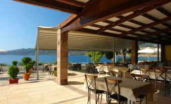 a restaurant patio overlooking the ocean , with tables and chairs set up for dining under a canopy at Golden View