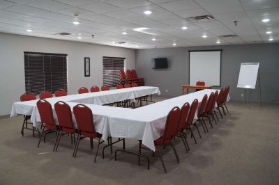 a conference room with a long table surrounded by red chairs and a projector screen at Country Inn & Suites by Radisson, Watertown, SD