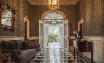 a grand entrance hall with a black and white checkered floor , a couch , and a chandelier at Leixlip Manor Hotel