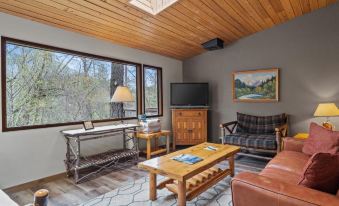 a cozy living room with wooden furniture , including a couch , chairs , and a tv . also a dining table in the room at Weasku Inn