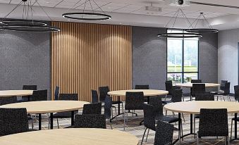a modern conference room with wooden tables and chairs , large windows , and pendant lights hanging from the ceiling at Holiday Inn & Suites Hopkinsville - Convention Ctr