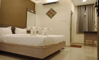 a neatly made bed with white linens and a towel on top is in a room with a window at Jayam
