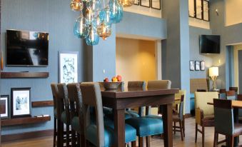 a dining room with a long wooden table surrounded by chairs , and a tv mounted on the wall at Hampton Inn & Suites by Hilton Stroudsburg Pocono Mountains