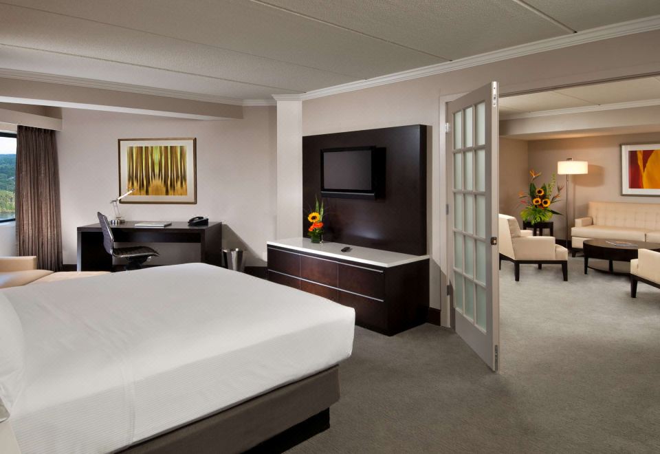 a modern hotel room with a large bed , white sheets , and a flat - screen tv on the wall at Hilton Albany