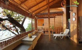 a wooden deck with a thatched roof and several chairs , creating a comfortable outdoor living space at Chareena Hill Beach Resort
