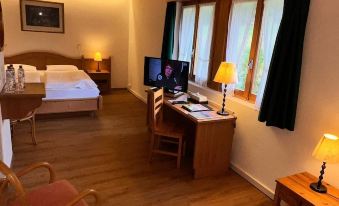 a hotel room with wooden floors , white walls , and large windows , featuring a bed , desk , chairs , and a desk with a compu at Hotel Roc et Neige