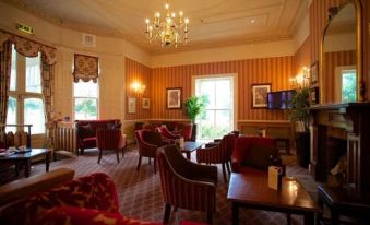 a well - decorated living room with multiple couches , chairs , and tables arranged in a sitting area at Coulsdon Manor Hotel and Golf Club