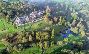 a bird 's eye view of a golf course with trees , water , and buildings in the background at Bovey Castle