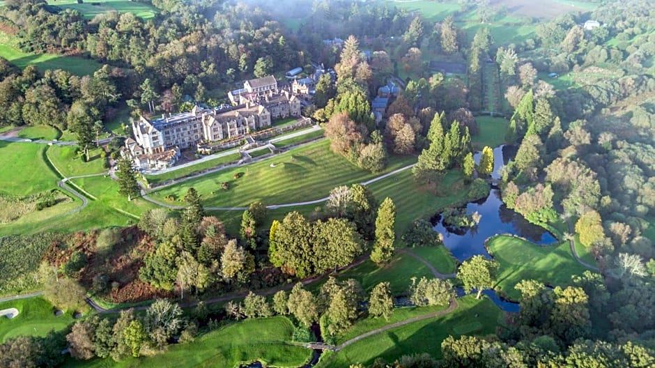 a bird 's eye view of a golf course with trees , water , and buildings in the background at Bovey Castle
