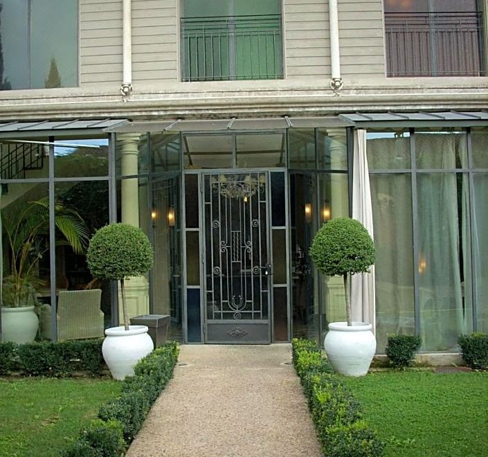 a modern building with glass doors and windows , green bushes , and white flowerpots on either side of the entrance at La Maison Navarre