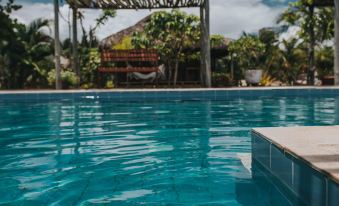 a large swimming pool with a wooden structure in the background , surrounded by lush greenery at Ventana Hotel